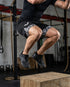 Person performing a jump exercise on a wooden box in a gym setting